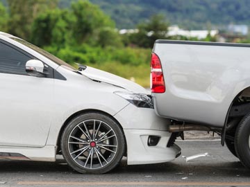 Unfallwagen Ankauf in Augsburg – Schnell, fair und unkompliziert Ein weißer Sedan wird von einem silbernen Pickup auf einer Straße aufgefahren, wobei der vordere Teil des Sedans sichtbare Schäden aufweist.